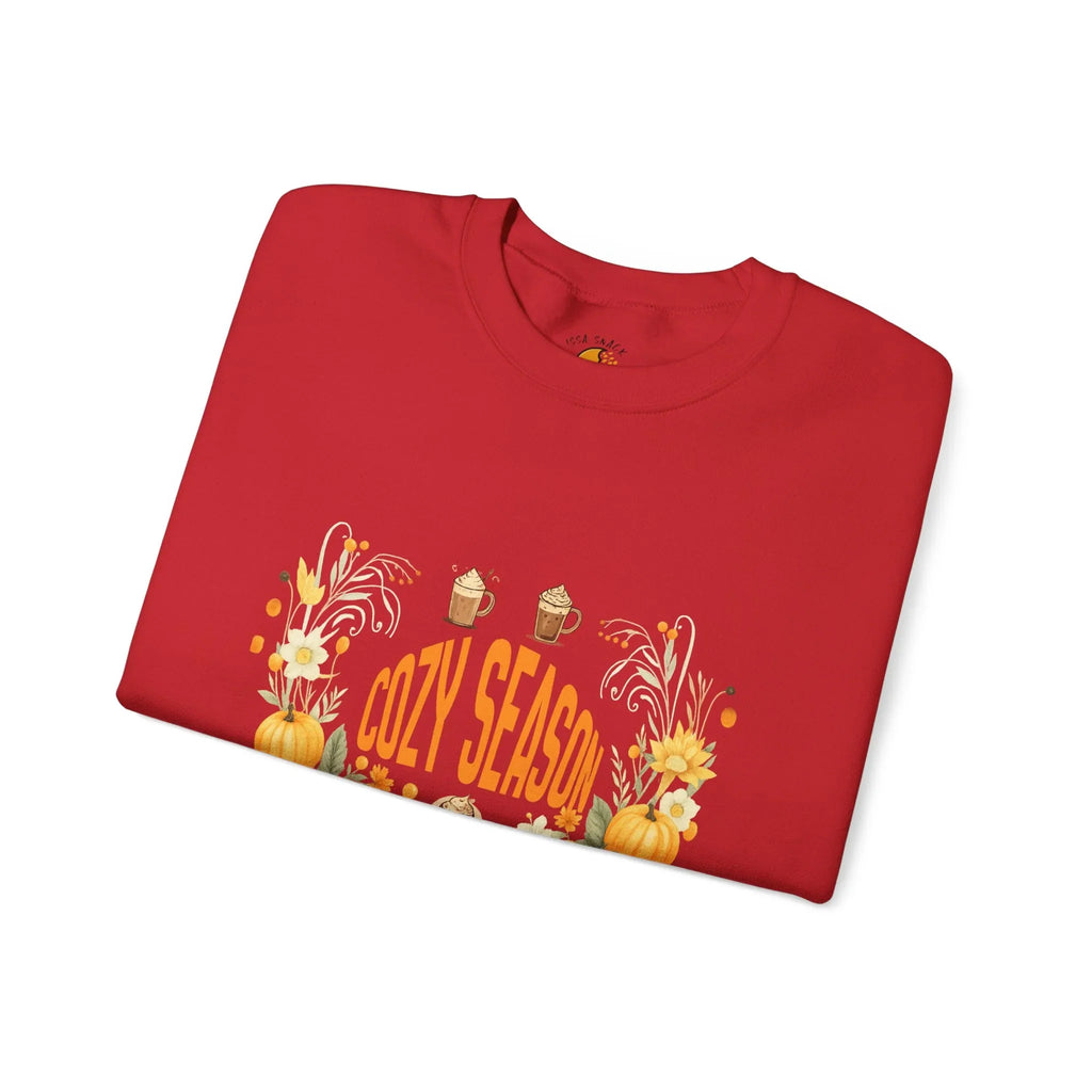 Red folded sweatshirt with Cozy Season text, pumpkins, flowers, and mugs graphic design