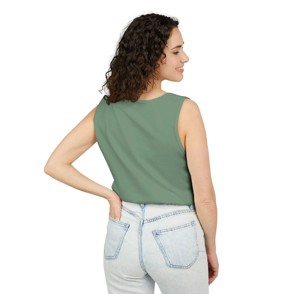 Woman in green sleeveless top and light denim jeans standing against white background