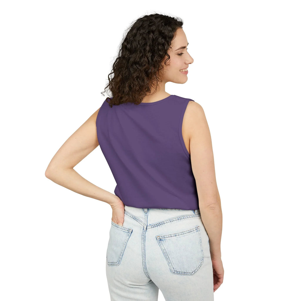 Woman in a sleeveless purple top and light blue jeans, standing with hand on hip