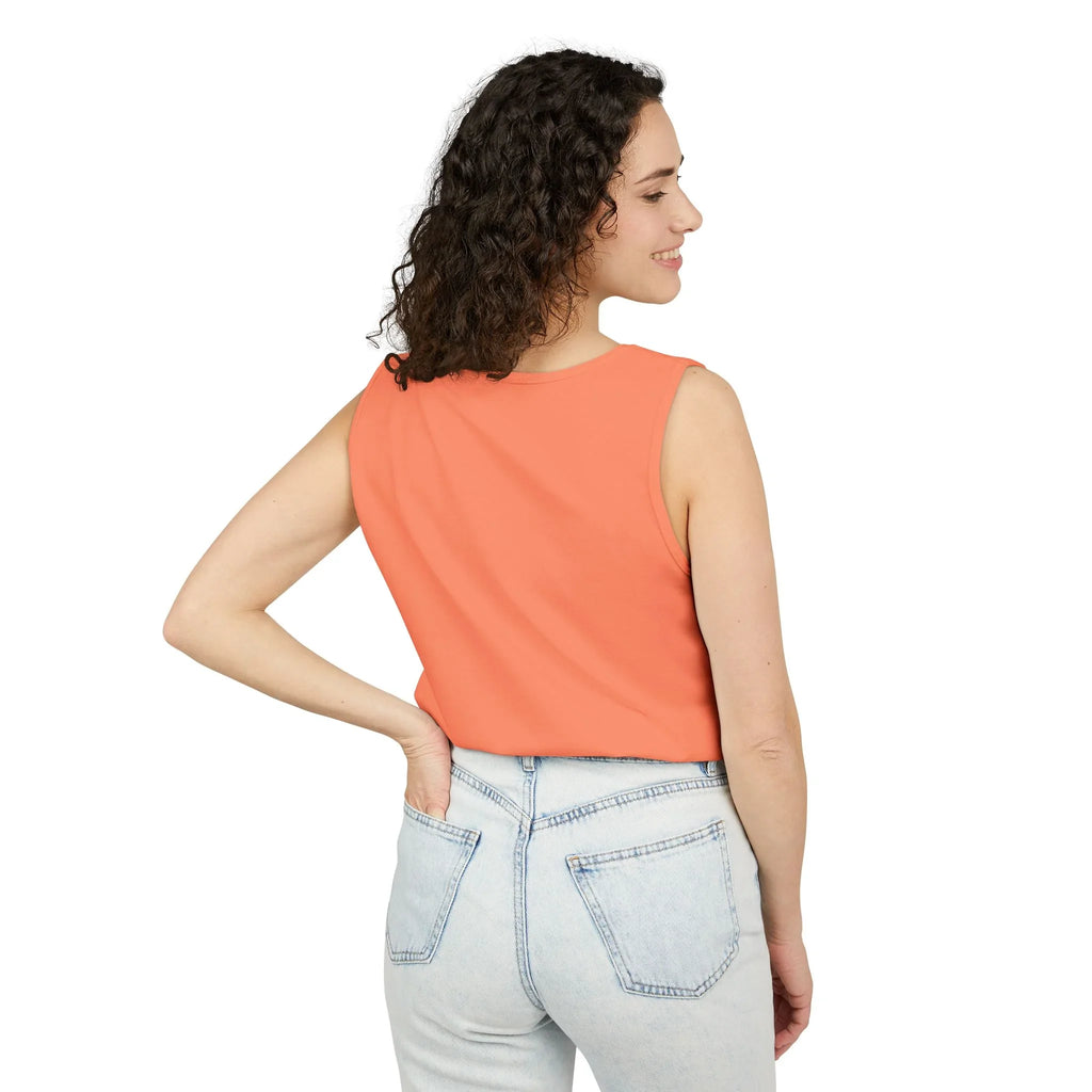 Woman in orange sleeveless top and light blue jeans standing against white background