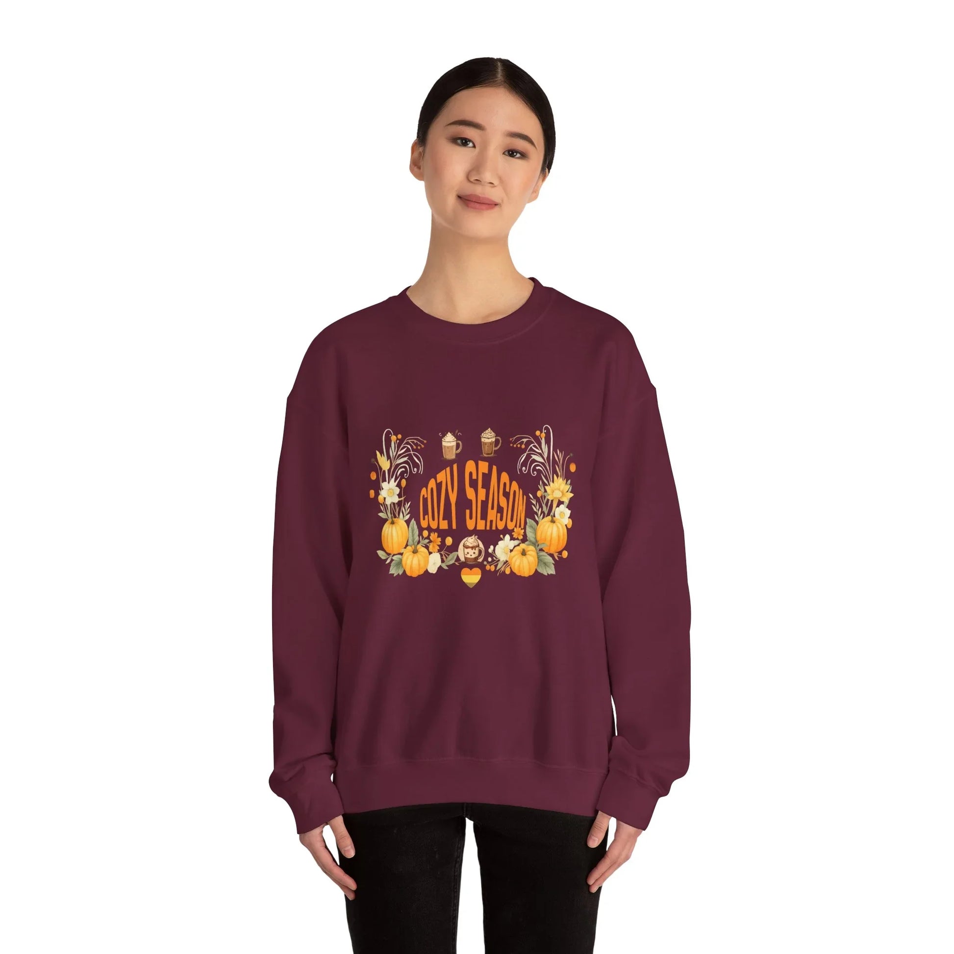 Woman wearing maroon cozy season sweatshirt with pumpkins and fall-themed graphic