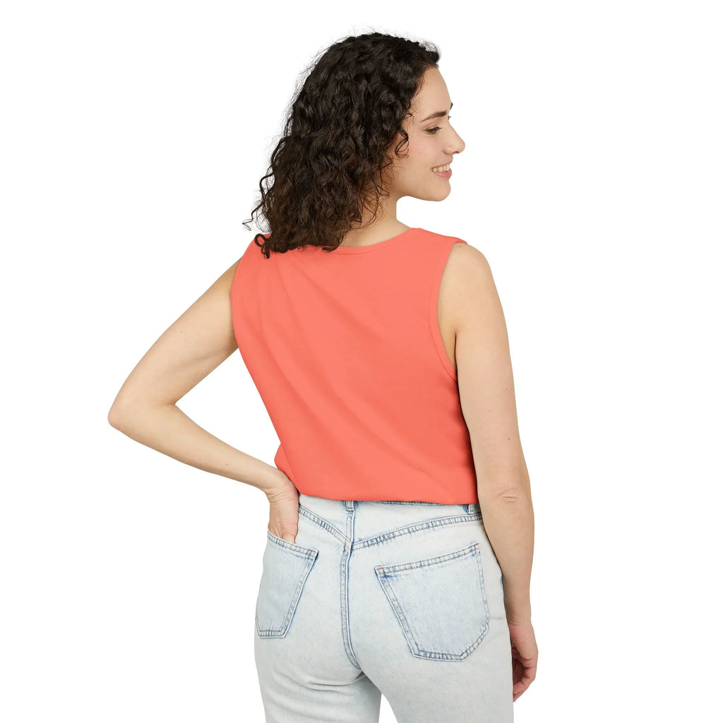 Woman in coral sleeveless top and light blue jeans posing against white background