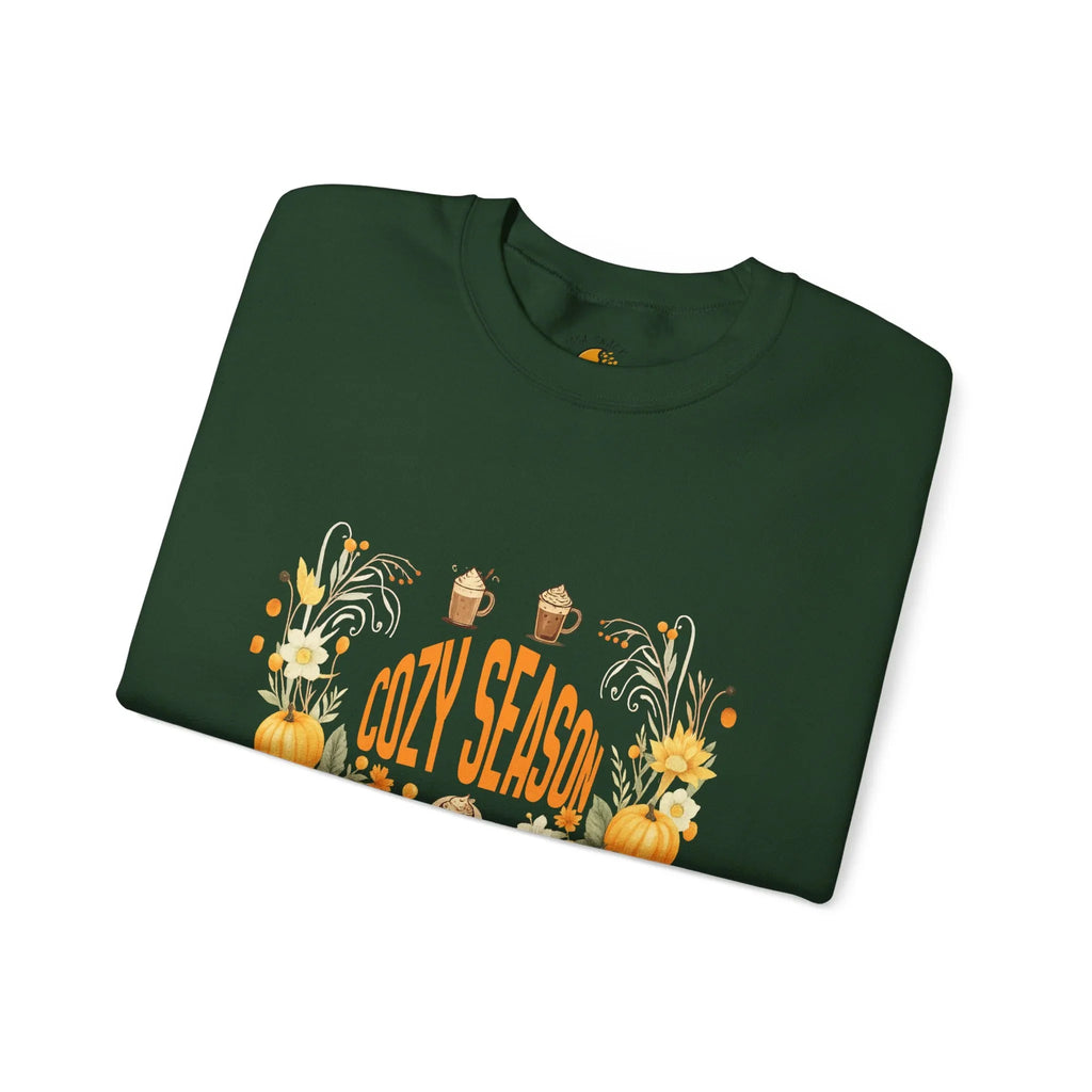 Green sweatshirt with 'Cozy Season' text, pumpkins, mugs, flowers, and autumn decor